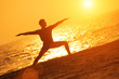 Man in yoga warrior pose on sunset ocean beach