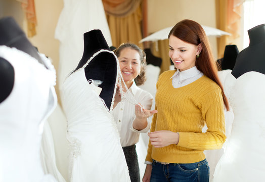 pretty bride chooses bridal outfit at wedding store