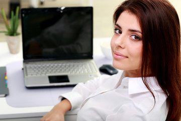 Happy young businesswoman sitting at the table