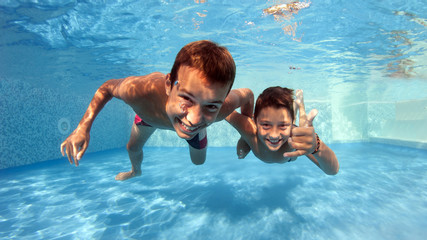 Underwater brothers portrait in swimming pool.