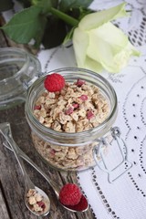 Granola with raspberry and flower on a rustic background