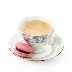 Pink macaroon on a saucer with cup of coffee