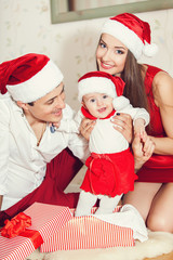 Fototapeta premium Happy family with cute baby in suit of Santa's little helper
