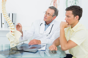 Obraz premium Doctor explaining spine to a patient in office