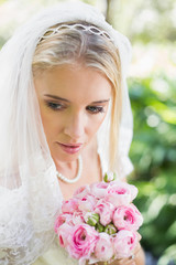 Obraz premium Smiling bride wearing veil holding bouquet looking down