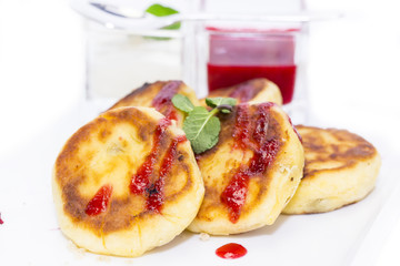 cheesecakes with sour cream and jam on table in restaurant
