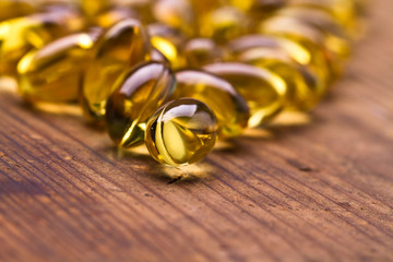 Cod liver oil omega 3 gel capsules isolated on wooden background