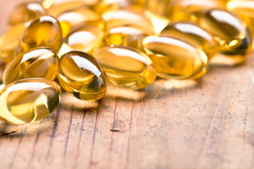 Cod liver oil omega 3 gel capsules isolated on wooden background