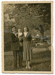 Couple with their child between fruit trees - circa 1950