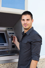 Handsome young man put his credit card at the ATM