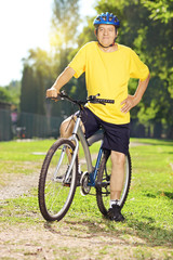 Full length portrait of a middle aged man posing on his bicycle