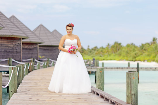 Bride in wedding dress posing near the water villas