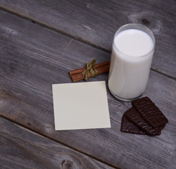 Glass of milk with cinnamon and chocolate with blank paper