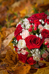 The wedding bunch of flowers lies on fallen leaves.
