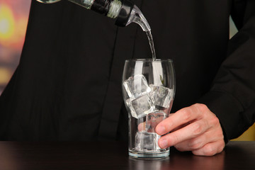 Bartender making cocktail on bright background, close-up