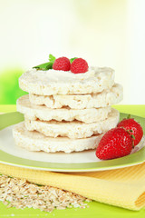 Tasty crispbread with berries on plate, on green table