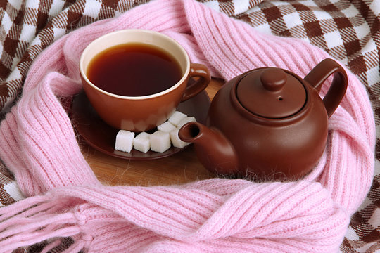 Cup and teapot with scarf on fabric background