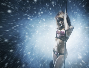 Beautiful and sexy striptease dancer on a snowy background
