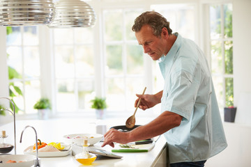 Middle Aged Man Following Recipe On Digital Tablet