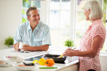 Middle Aged Couple Cooking Meal In Kitchen Together
