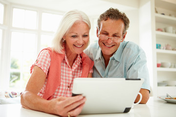 Fototapeta na wymiar Smiling Middle Aged Couple Looking At Digital Tablet
