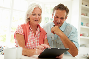 Smiling Middle Aged Couple Looking At Digital Tablet