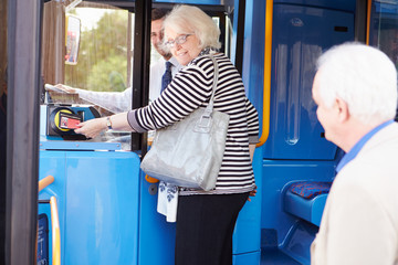 Senior Couple Boarding Bus And Using Pass