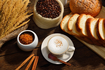 A cup of cappuccino with coffee beans and bread.