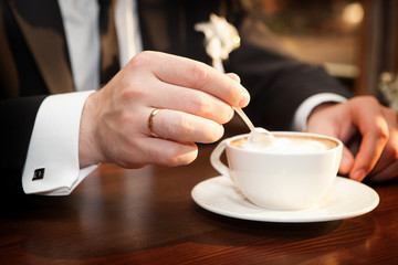 Man stirs sugar in a cup of coffee
