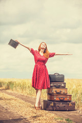 Redhead girl with suitcases at outdoor