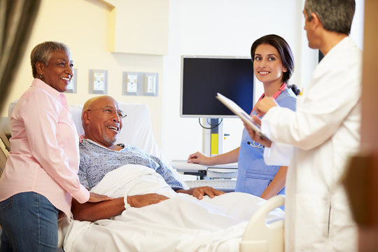 Medical Team Meeting With Senior Couple In Hospital Room