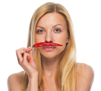 Portrait of teenage girl holding red chili pepper as mustage