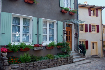 Fototapeta na wymiar Cute flowering doors and windows in houses of Ardeche, France