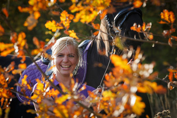 Reiterin lächelt durch Herbstblätter