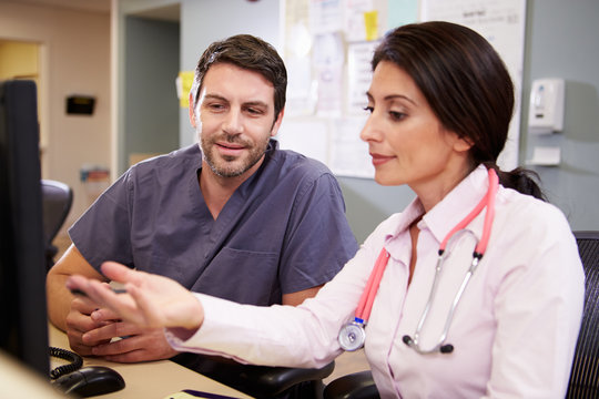 Female Doctor With Male Nurse Working At Nurses Station