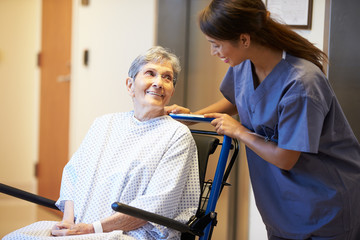 Senior Female Patient Being Pushed In Wheelchair By Nurse