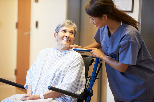 Senior Female Patient Being Pushed In Wheelchair By Nurse