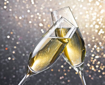 champagne flutes with golden bubbles on light bokeh background