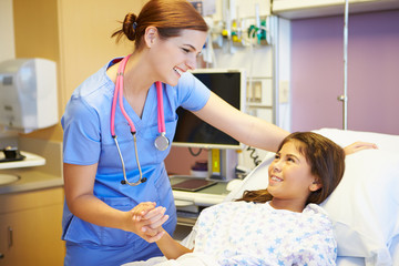 Young Girl Talking To Female Nurse In Hospital Room