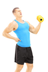 Naklejka premium Young guy with back pain while lifting a dumbbell