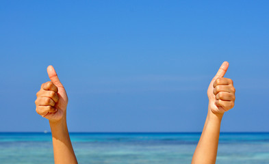 Two hands with thumb up on blue sky and sea background