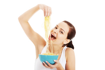 Beautiful woman eating pasta from a bowl.
