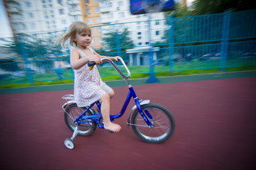 Adorable girl ride on bike with training wheels on playground