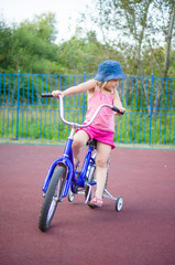 Adorable girl ride on bike with training wheels on playground