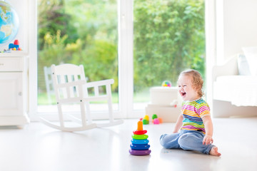Happy laughing toddler girl playing in a white room with a big w