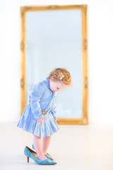 Funny toddler girl with beautiful curly hair wearing a blue dres