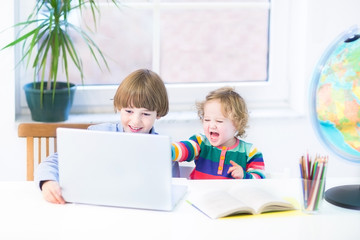 Funny laughing kids , a boy and his toddler sister, playing toge