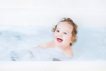 Funny toddler girl having a bath with foam