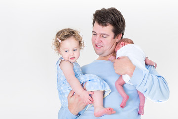 Young father holding a curly toddler girl and a newborn baby