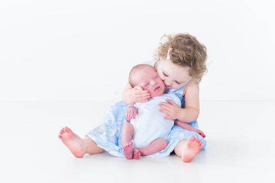 Sweet toddler girl kissing her newborn baby brother